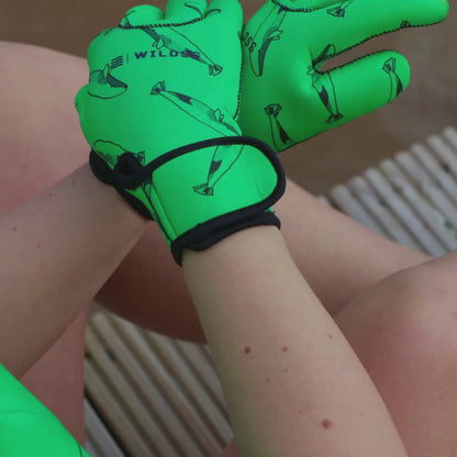 Video of woman wearing green whale print neoprene gloves and removing them with the velcro wrist strap