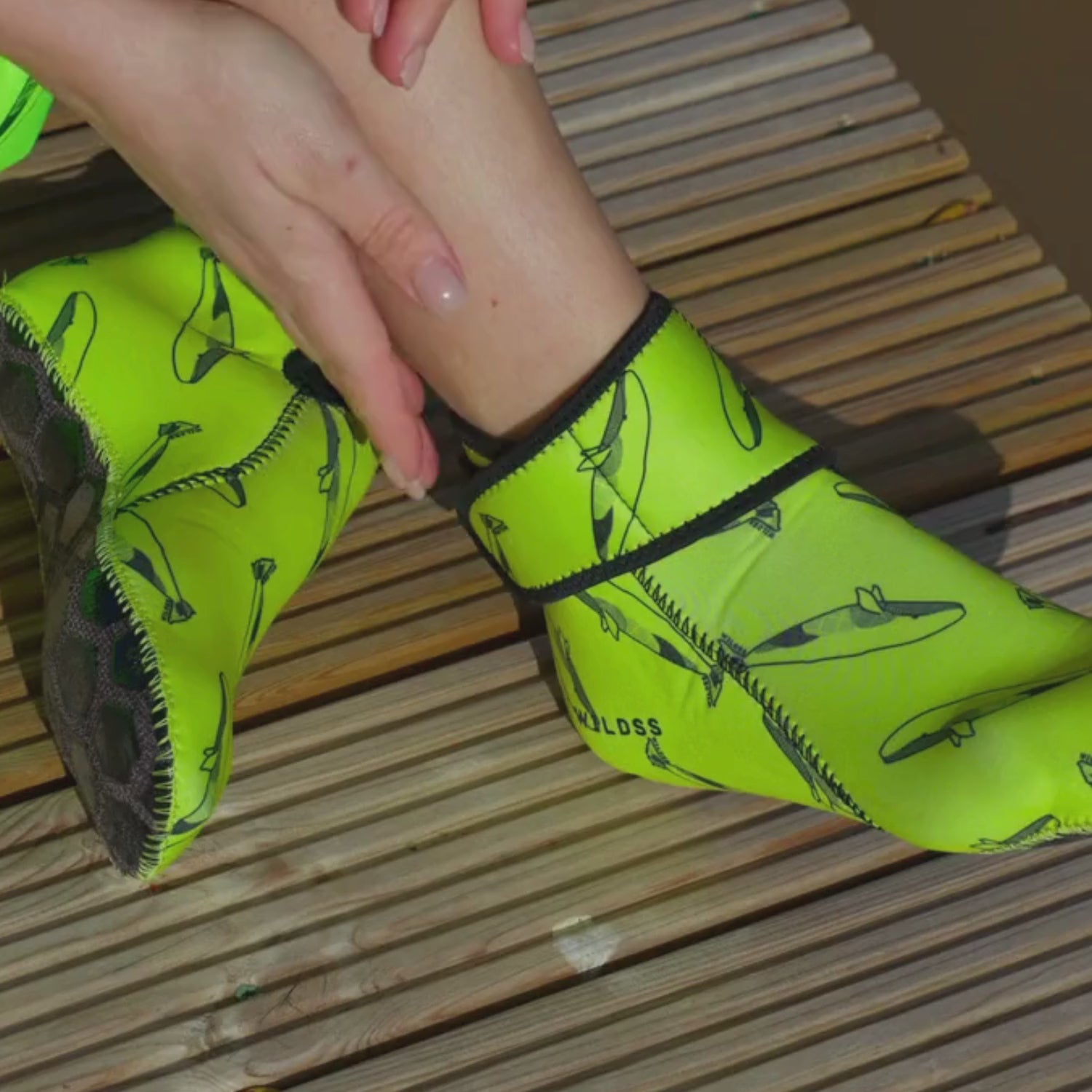 Video of woman wearing yellow whale print neoprene socks and removing them with the velcro ankle strap
